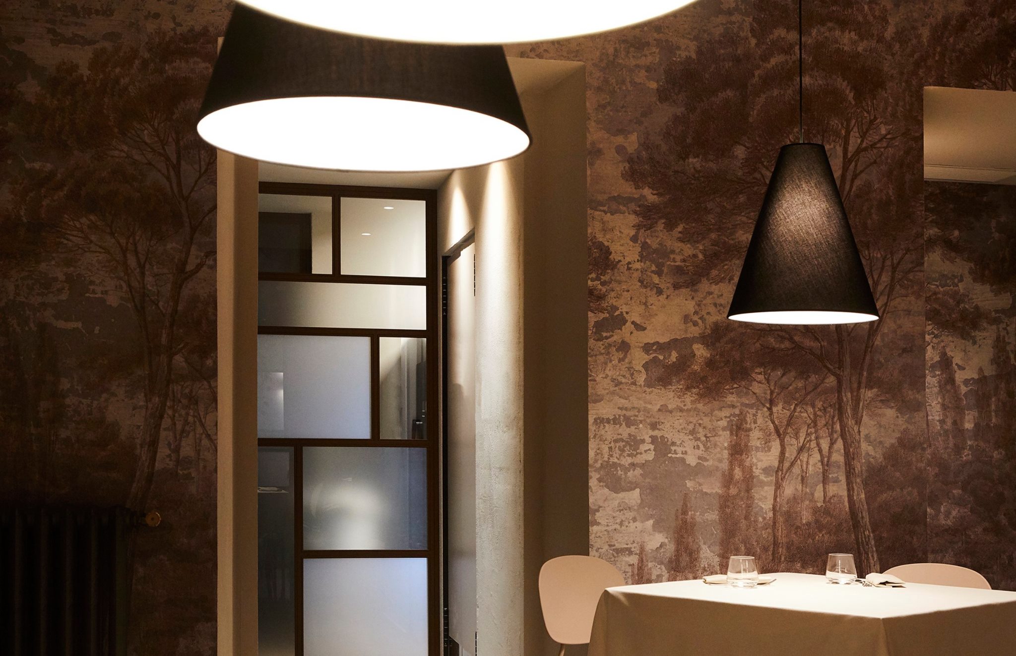 In this hospitality interior designer project, restaurant EraGoffi was given a new lease of life with pared-back, restrained lines and contemporary shapes. The image shows detail of its lighting, wallpaper and door.
